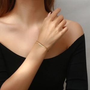 Close-up of a double-layer gold snake chain and beaded bracelet on a woman's wrist