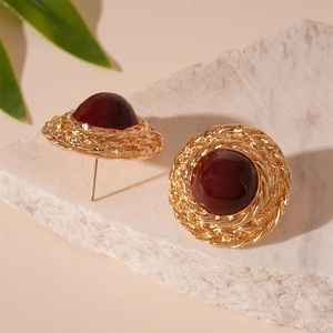 Vintage gold woven stud earrings with deep red dome gems on a stone background