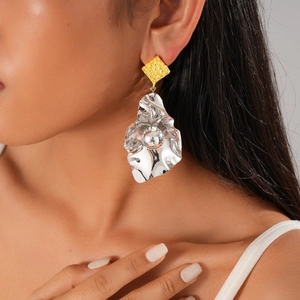 Macro shot of irregular silver metallic leaf pendant with a textured golden square stud