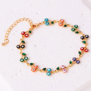 Dettaglio di bracciale dorato con ciondoli a ciliegia in smalto colorato e occhio