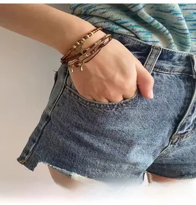 Détail de bracelets bohèmes superposés avec perles brunes et pendentifs étoiles dorés