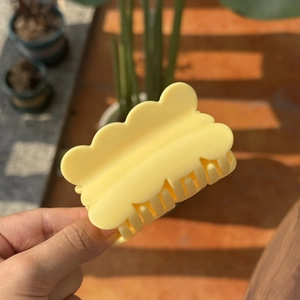 Elegant yellow cloud-shaped plastic hair claw clip for women in natural outdoor lighting