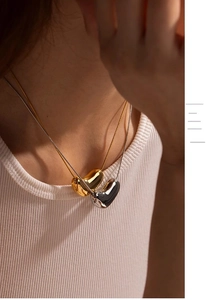 Close-up of layered gold and silver bean necklaces with polished snake chain on model
