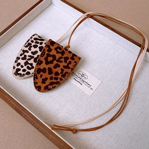 Detailed view of leopard print faux leather shield pendants on bohemian necklace cords