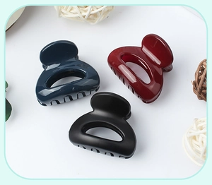 Close-up of small matte hollow semi-circular hair claws in navy, deep red, and black