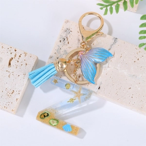 Detail of resin letter Z keychain with real shells, sand, and blue tassel on stone base