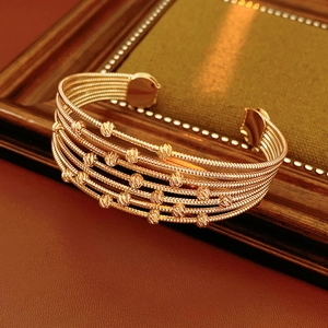 Détail du bracelet ouvert doré à plusieurs rangs avec des perles métalliques facettées