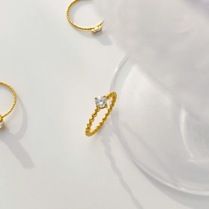 Detail of 18K gold plated beaded band ring with a central sparkling square zircon inlay