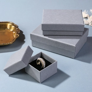 Detailed view of gray textured jewelry boxes with black sponge lining and pearl rings