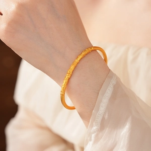 Close-up of vintage brushed gold bangle with detailed floral engraving on wrist