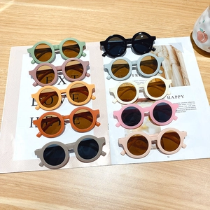 Cute round frame kids sunglasses in multiple pastel colors on a stylish magazine