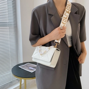 Detail of white quilted crossbody bag with resin chain and patterned fabric strap