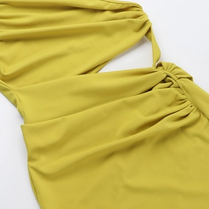 Detailed macro shot of yellow ruched fabric and hollow cut-out design on a slim-fit dress