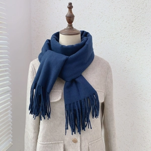 Detail of dark blue cashmere-like scarf with fringe elegantly styled on a model