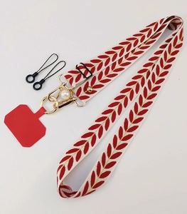 Detail of red leaf pattern crossbody phone strap with gold hardware and pearl charm