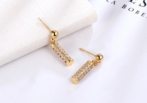 Detail of gold cylinder earrings with pavé set micro zircons and spherical stud design