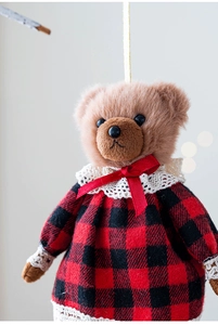 Close-up of plush teddy bear pendant in red plaid dress with white lace trim detail