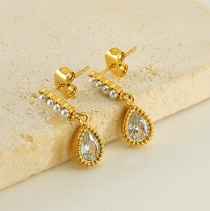 Detail of 18K gold teardrop earrings with a row of pearls and sparkling zircon stone