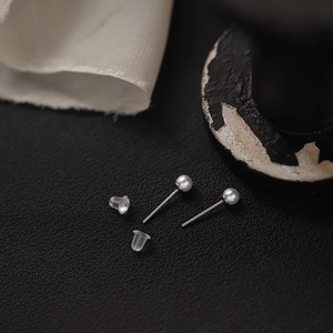 Macro view of silver titanium pearl bear earrings with clear silicone backings