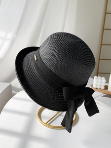 Détail du chapeau de paille noir avec ruban élégant et petite plaque en métal doré