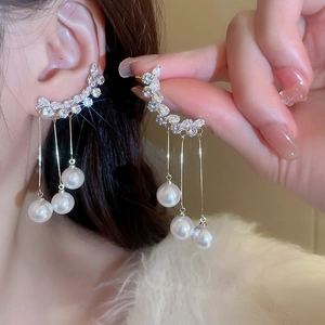Detail of long gold tassel earrings with sparkling crystals and round white pearls