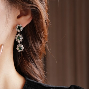 Detailed view of silver sunflower earrings with three layers of green and clear crystals