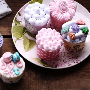 Close-up of decorative cupcake paper liners with cream topping on a floral ceramic plate