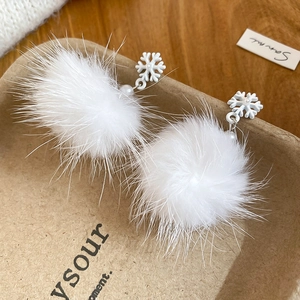Dettaglio di pompon bianchi in peluche e ciondoli a fiocco di neve con perle eleganti