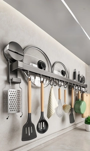 Wall-mounted kitchen storage rack with hooks holding various utensils like spatulas