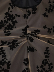 Détails de flocage floral en velours noir sur mesh beige avec plis drapés élégants
