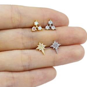 Vue macro de petits clous d'oreilles en or et argent avec zircon sur le doigt