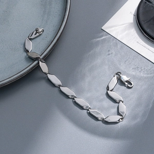 Polished silver stainless steel chain link bracelet with lobster clasp on ceramic plate
