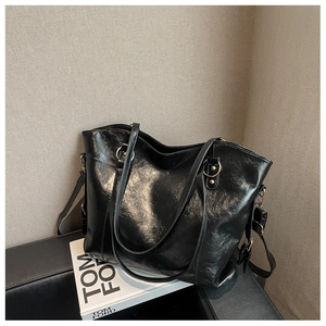 Detail of a large black tote bag with wax leather texture and sleek metal buckles