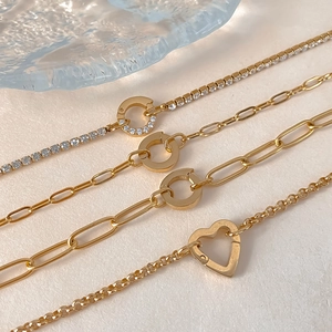 Close-up of four gold-plated titanium steel bracelets with heart and crystal details