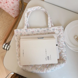 Detailed close-up of quilted floral cotton handbag with soft pink patterns and book
