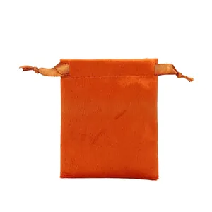 Macro detail of soft orange velvet jewelry drawstring pouch with satin ribbon closure
