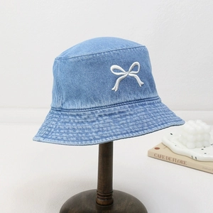 Détail de broderie nœud blanc 3D sur un chapeau bob en jean bleu clair sur un support