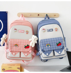 Detail of pink and blue canvas school backpacks featuring cartoon charms and embroidery