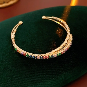 Macro shot of colorful cubic zirconia cross open bracelet on green velvet display