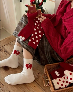 Detailed knit texture of red and white Christmas socks with apple patterns and warm bows