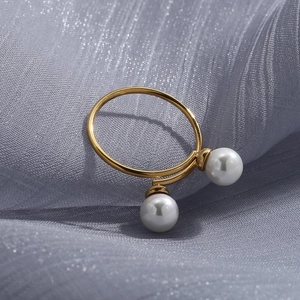 Detail of 18K gold-plated bypass ring with dual pearls on glossy purple fabric
