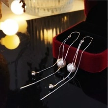 Gros plan de boucles d'oreilles pendantes en argent avec perles sur écrin rouge