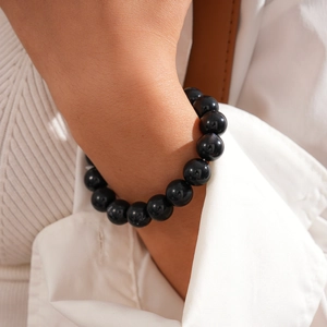 Close-up of minimalist black beaded bracelet with natural obsidian luster on model wrist
