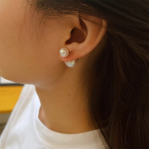 Close-up of elegant double pearl earrings worn by a model in warm indoor lighting