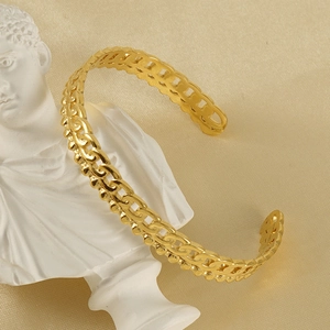 Détail macro d'un bracelet jonc évidé plaqué or 18K sur un buste en marbre blanc