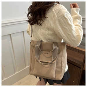 Detail of khaki nylon tote bag showing double handles and adjustable shoulder strap for daily use