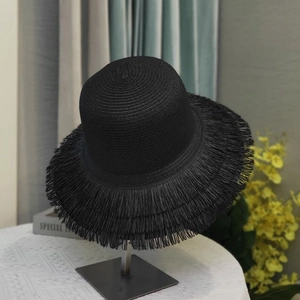 Detail of black straw hat with long fringe brim on a display stand for sun protection