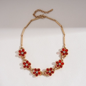 Detailed macro view of vintage golden chain with red glass flowers and crystal inlay