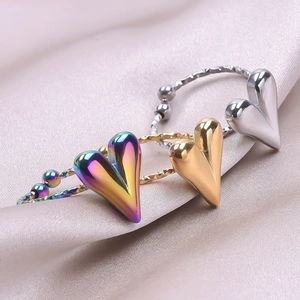 Detailed close-up of heart-shaped rings in rainbow, gold, and silver on pink satin