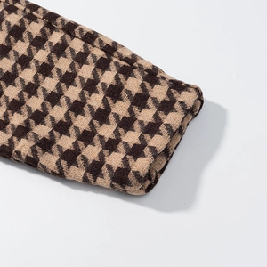 Detailed macro view of houndstooth wool fabric texture on jacket cuff for women